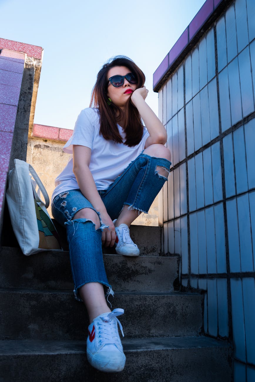 woman sitting on stairs beside tote bag